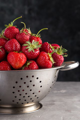 Fresh juicy strawberries from the garden in an iron bowl on the table. Heap of fresh strawberries in an iron bowl on rustic white wooden background. Fresh organic berries macro. Free space for text.