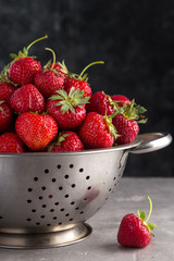 Fresh juicy strawberries from the garden in an iron bowl on the table. Heap of fresh strawberries in an iron bowl on rustic white wooden background. Fresh organic berries macro. Free space for text.