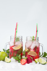 Cold lemonade with strawberries, mint and lime. On a white background, decorated with strawberries, lime, mint and ice.