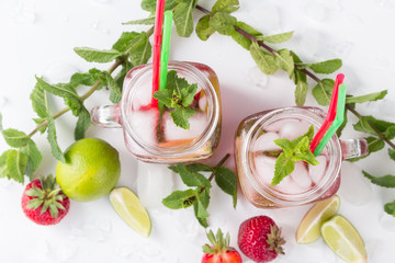 Cold lemonade with strawberries, mint and lime. On a white background, decorated with strawberries, lime, mint and ice.