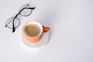 Office desk table with coffee cup, pen and glasses. Top view with copy space