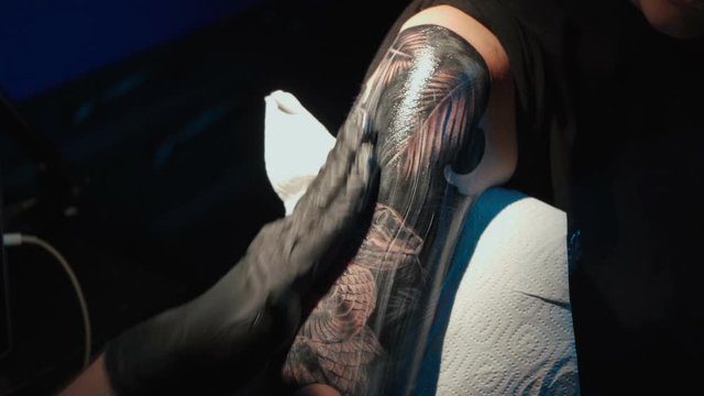 Close up video of man doing black tattoo on woman in studio