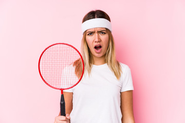 Young woman playing badminton isolated screaming very angry and aggressive.
