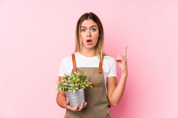 Young caucasian gardener woman in a pink background having some great idea, concept of creativity.