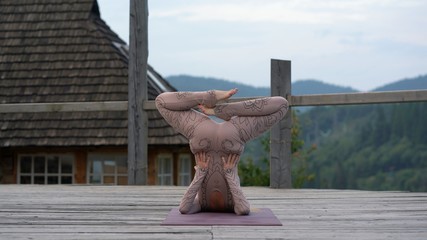 A woman practices yoga at the morning in a terrace on a fresh air.