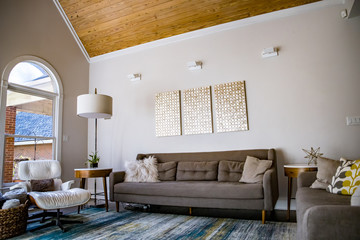 Mid century modern contemporary style living room den in a spacious open home with a vaulted ceiling and a pine wood ceiling and neutral gray couch and furniture