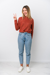 Full body young caucasian woman joyful and carefree showing a peace symbol with fingers.
