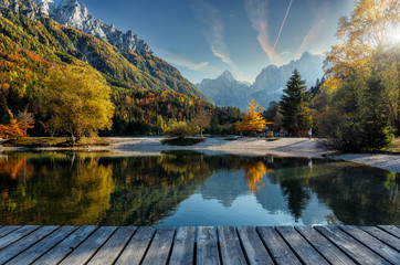 Amazing nature Landscape in Julian Alps during sunset. Lake Jasna near Kranjska Gora, Slovenia. Crystal clear alpine with colorful trees and mountain peaks in background. Triglav national park