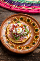 Mexican ham toast also called tostadas with beans and cheese on wooden background