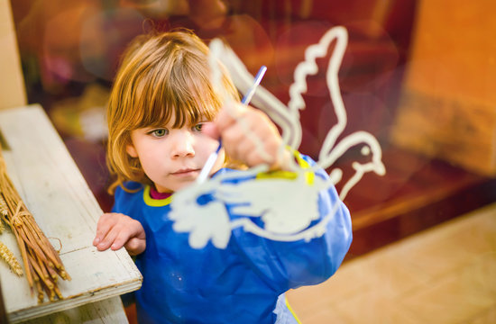 portrait of a pretty little girl painting a dove of peace