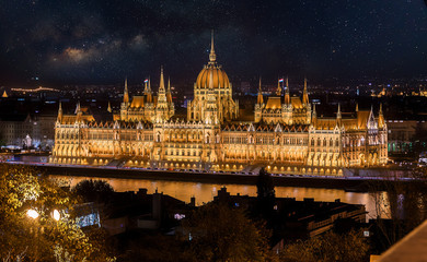 Fototapeta na wymiar Colorful sunset over Budapest with fantastic sky star and milky way. Night view of the illuminated building of the Hungarian parliament over Danube river with reflected. Popular touristic locations