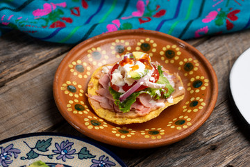 Mexican ham toast also called tostadas with beans and cheese on wooden background