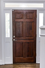 Solid wood dark stained front door in a home with vaulted ceilings and transom windows