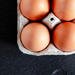 Large brown chicken eggs lie in an eco-friendly cardboard egg tray