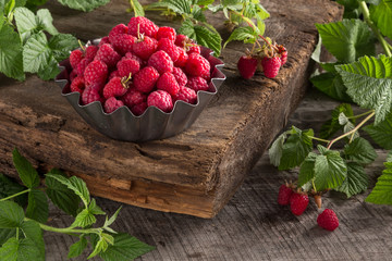 Raspberry. Fresh juicy berries from the garden in an iron pot on a wooden table. Raspberry With green leaves. Fresh organic berries macro View from above. Top view. Close-up photo.