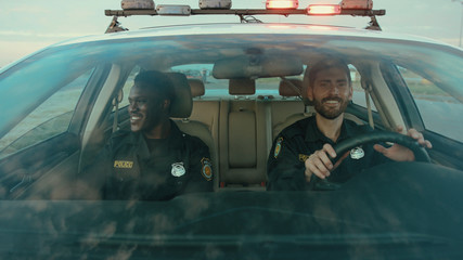 Two professional cops afro-american driving a high speed car patroling the city. Front view severe...