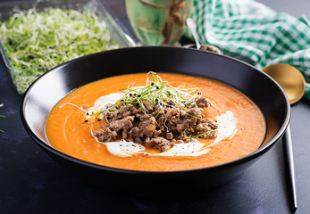 Delicious cream of pumpkin soup with roasted forcemeat made of beef minced meat in a bowl on a dark table. Thanksgiving Day.
