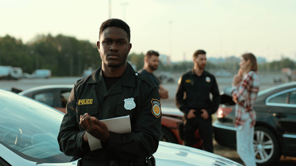 Confident serene african american cop with papers looking on camera looking serious leaning on the...