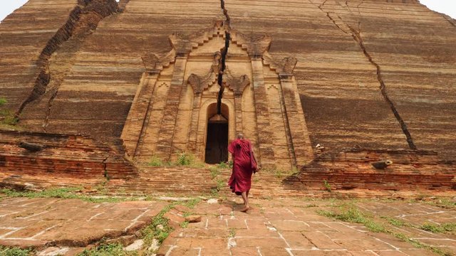 Asian Monk Walking In Front Of Burmese Ancient Buddhist Temple. 4K Slow Motion Footage. Mandalay, Myanmar.