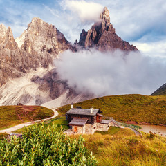 Wonderful Sunny Scenery of Dolomites mountains. Baita Segantini mountain refuge with Cimon della Pala peak during sunset. Amazing Nature Landscape. Rolle pass, Trentino province, Italy, Europe