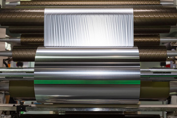 roll of aluminum foil for food packaging on the automatic packing machine in food product factory. industrial and technology concept.