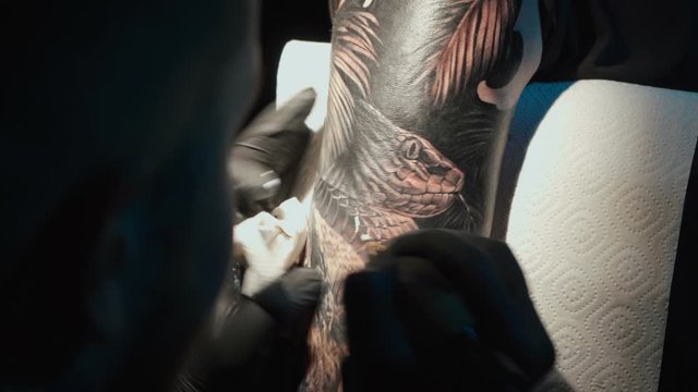 Close up video of doing black tattoo of snake on woman