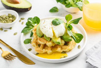 Poached egg on cheese waffles with corn salad and avocado for breakfast. Healthy food. Selective focus