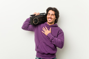 Fototapeta premium Young urban man holding a guetto blaster laughs out loudly keeping hand on chest.