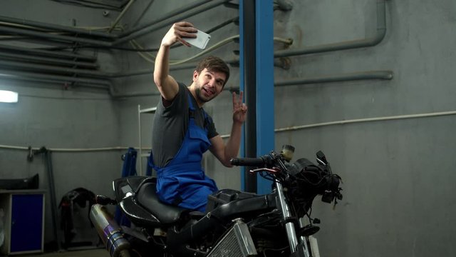 Technician sits on motorcycle and makes a photo 