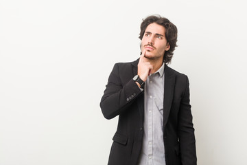 Young business man against a white background looking sideways with doubtful and skeptical expression.