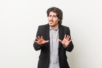 Young business man against a white background rejecting someone showing a gesture of disgust.