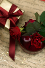 red roses in a vase with a gift box on a background. Space for copy