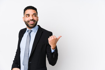 Young latin business woman against a white background isolated points with thumb finger away, laughing and carefree.