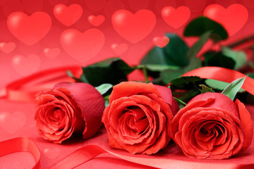 Red roses next to a red ribbon, on a red background with bokeh hearts. Concept card for Valentine's Day. Copy space