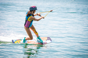 Girl focused on wakeboarding on a lake - obrazy, fototapety, plakaty