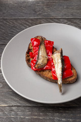 Fish sandwiches with sprats. Sandwich with red bell pepper and sprats on a gray plate. A set of...