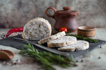 Spicy chicken roll on a grey dish with herbs. Slices of meatloaf on a beautiful plate.