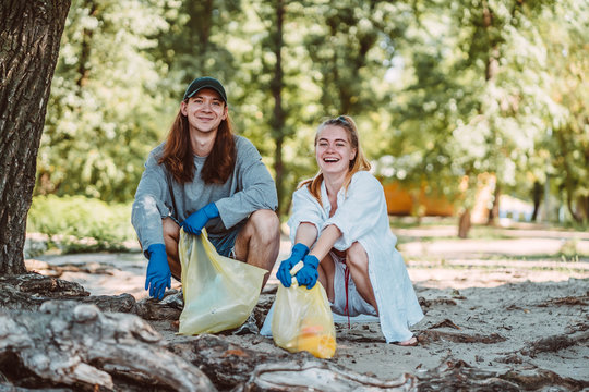 Man and Woman picking up trash from the park. They collecting the litter in garbage bag