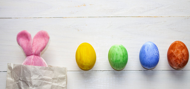 Easter eggs. Happy easter card. Multi-colored Easter eggs. Easter. Easter background. Easter eggs. Easter card. Easter greetings. Happy easter. Rabbit and eggs on a white wooden background. Banner, po