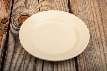 White plate on a wooden background. Close up.