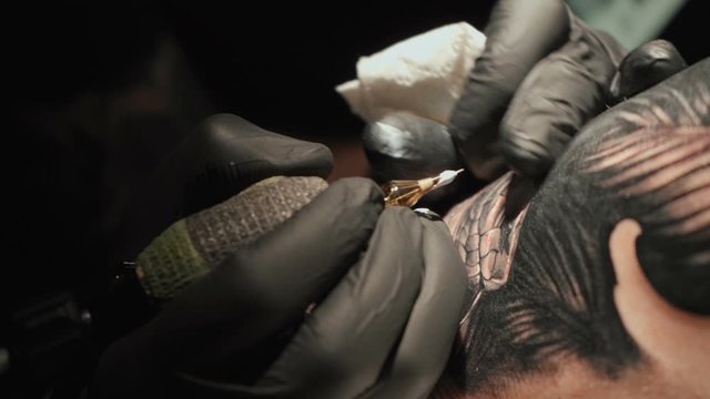 Close up video of man doing tattoo of snake on woman