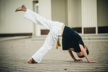 the boy is engaged in capoeira on the street