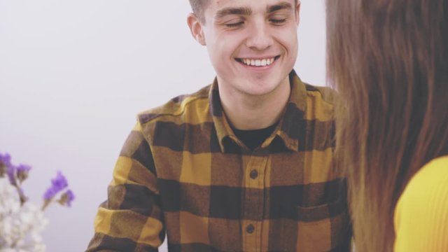 Loving man with a modest girl are talking in a loft cafe. Romantic date in a cafe. Man and woman are sitting at a table and holding hands of each other, in a cozy cafe. Action. Animation. 4K.