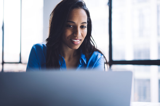 Smiling black woman reading information on laptop screen
