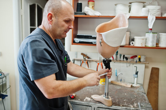 Prosthetist man making prosthetic leg while working in laboratory.