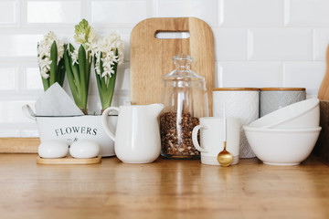 Kitchen utensils and dishware spring flowers on wooden table.