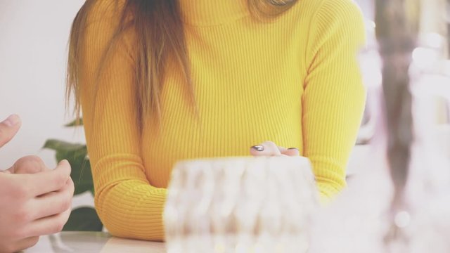 Adorable girl is sitting at the table in cafe. She is communication with her talkative boyfriend. Focus falls down on the vase. Close up. Copy space.