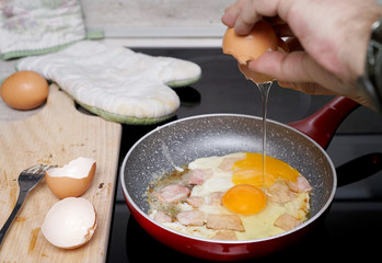 cracking eggs over a pan while making scrambled eggs