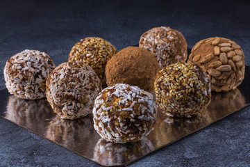 Homemade energy balls of their nuts, dried fruits and oatmeal, shot close-up, on foil and against a dark background