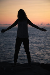 Fototapeta premium Vertical silhouette photo of happy girl on a beach